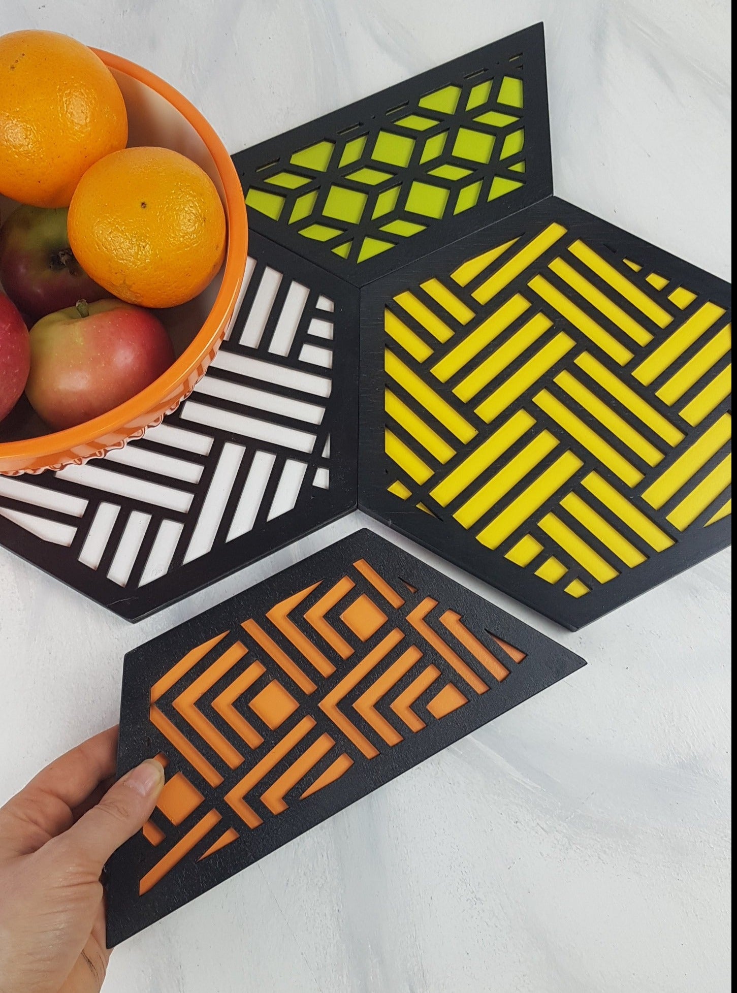 A person holding one of the lightweight and durable hexagonal trivets in their hand.