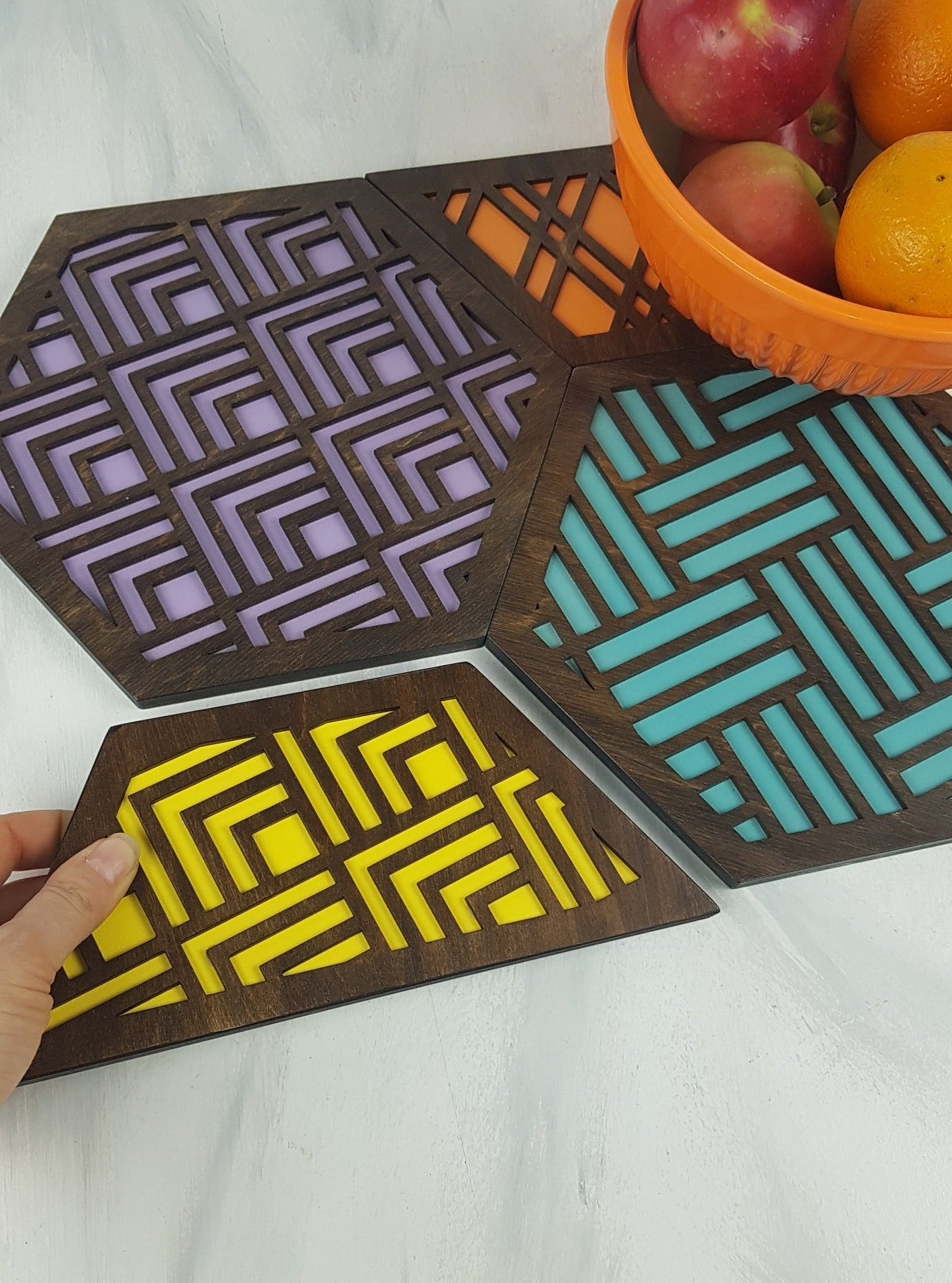 A person holding one of the lightweight and durable hexagonal trivets in their hand.