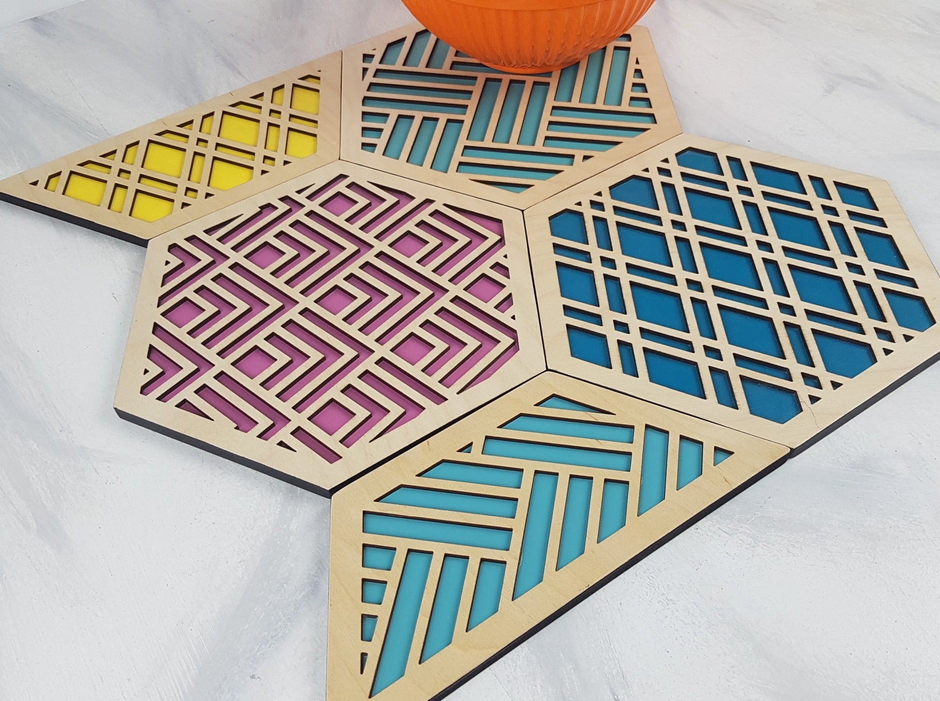 A set of hexagonal wooden geometric trivets with a mid-century modern pattern.